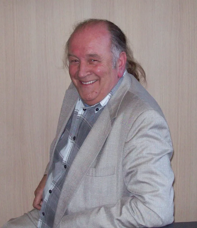 Portret van pianist Jos Lermyte, glimlachend in een lichtgrijs colbert